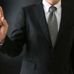 指を上に指しているスーツ姿の男性