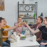 日本のシェアハウスで暮らす外国人の男女がリビングで乾杯をしている様子