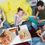 日本のシェアハウスで暮らしている男女がリビングでピザを食べている様子