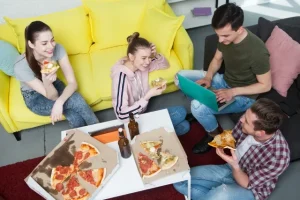 日本のシェアハウスで暮らしている男女がリビングでピザを食べている様子