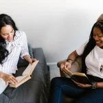 ルームシェアをしている外国人女性が仲良く本を読んでいる様子