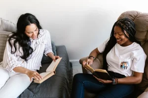 ルームシェアをしている外国人女性が仲良く本を読んでいる様子